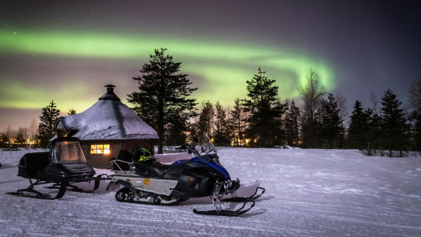 aurora over a snowy hut, two sleds