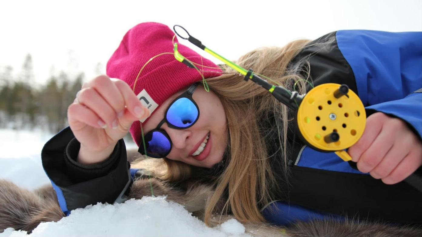 lying on the ice with a fishing rod